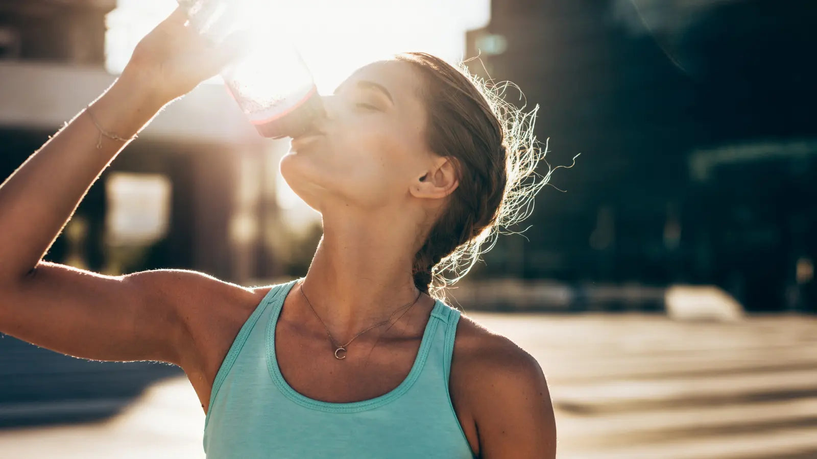 Woman drinking out of water bottle after workout.